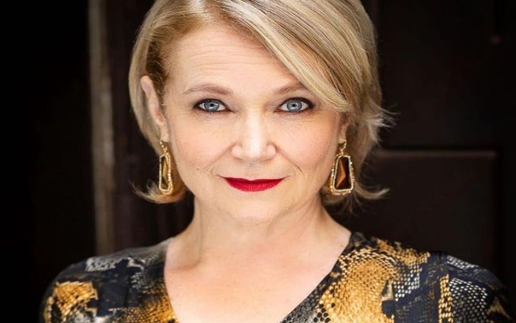 Geraldine Leer in a red lipstick and golden dress.